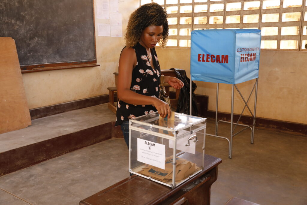 Une femme en train d'insérer un bulletin de vote dans une urne